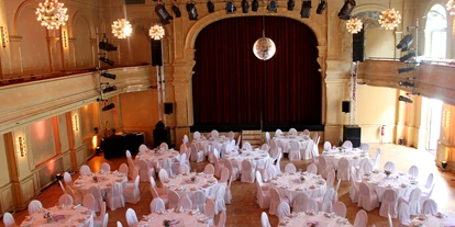 Winterhochzeit - Art der Location: Theater - Deutschland - Festlicher Ballsaal mit runden Tischen und Bankett-Bestuhlung mit weißen Stuhl-Hussen - Heimathafen Neukölln