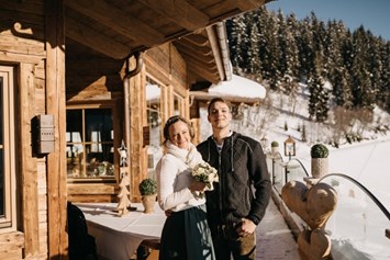 Hochzeitslocation: Das glückliche Brautpaar auf der Sonnenterrasse der Rössl Alm. - Rössl Alm