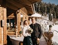 Hochzeitslocation: Das glückliche Brautpaar auf der Sonnenterrasse der Rössl Alm. - Rössl Alm