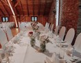 Hochzeitslocation: Brauttafel mit edlen Stuhlhussen vor der historischen Steinmauer  - Eventtenne - Hochzeits- & Veranstaltungslocation