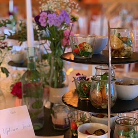 Hochzeitslocation: Vorspeisenbuffet auf den Gasttischen elegant angerichtet auf schönen Etageren - Eventtenne - Hochzeits- & Veranstaltungslocation