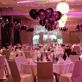 Hochzeitslocation: Runde Tische bestuhlt mit Hussen und farblich abgestimmten Ballons - Hotel Altes Stahlwerk