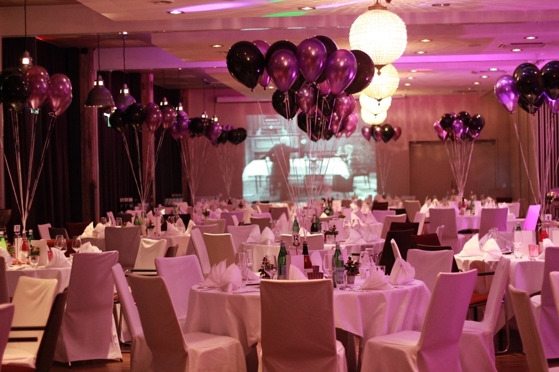 Hochzeitslocation: Runde Tische bestuhlt mit Hussen und farblich abgestimmten Ballons - Hotel Altes Stahlwerk