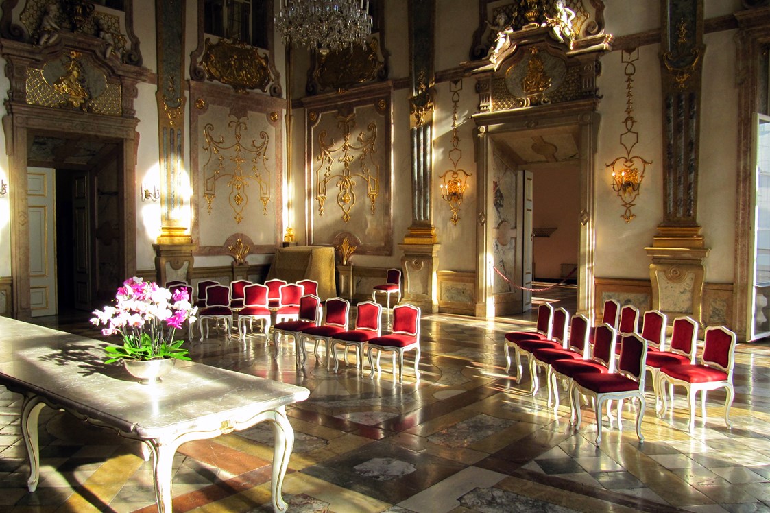 Hochzeitslocation: Der Marmorsaal wird oft als der schönste Trauungssaal Europas bezeichnet. Hier erwacht der weltberühmte Saal in dem schon W.A. Mozart mit seiner Familie musiziert hat im Morgenlicht.  - Schloss Mirabell